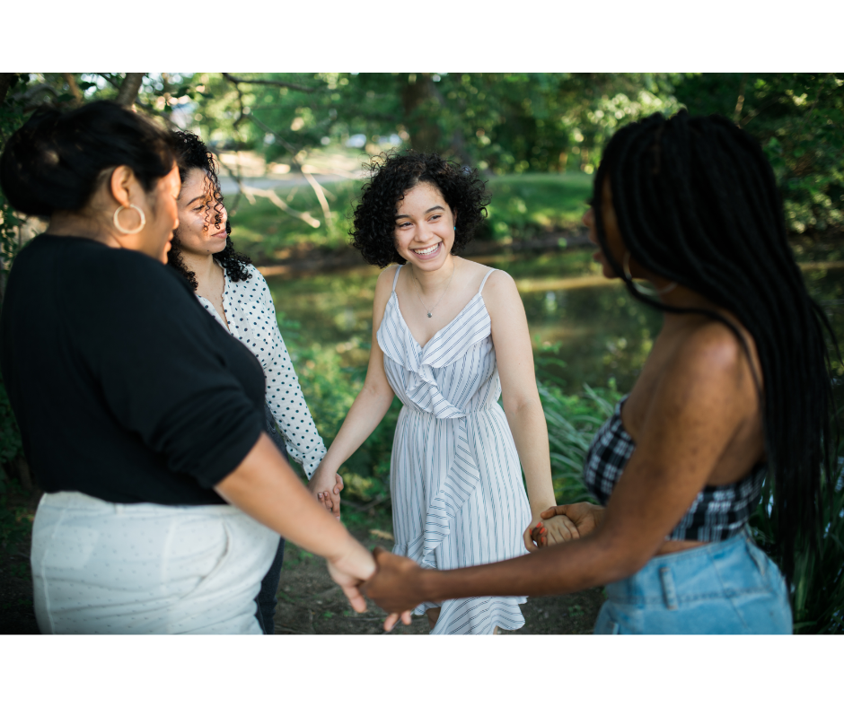 4 young women holding hands supportively in a circle